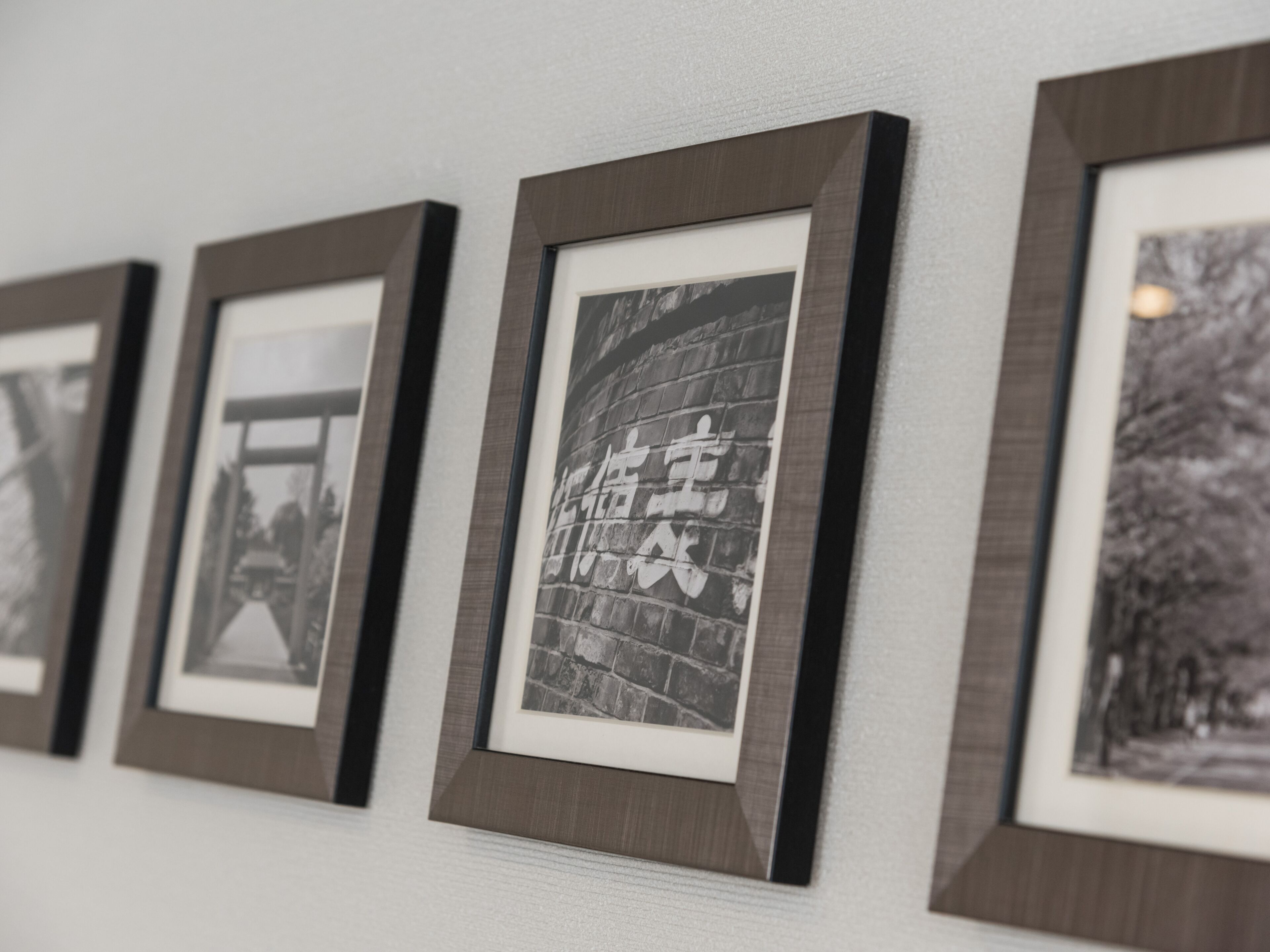 Een muur met ingelijste foto's in een galerie of tentoonstellingsruimte.