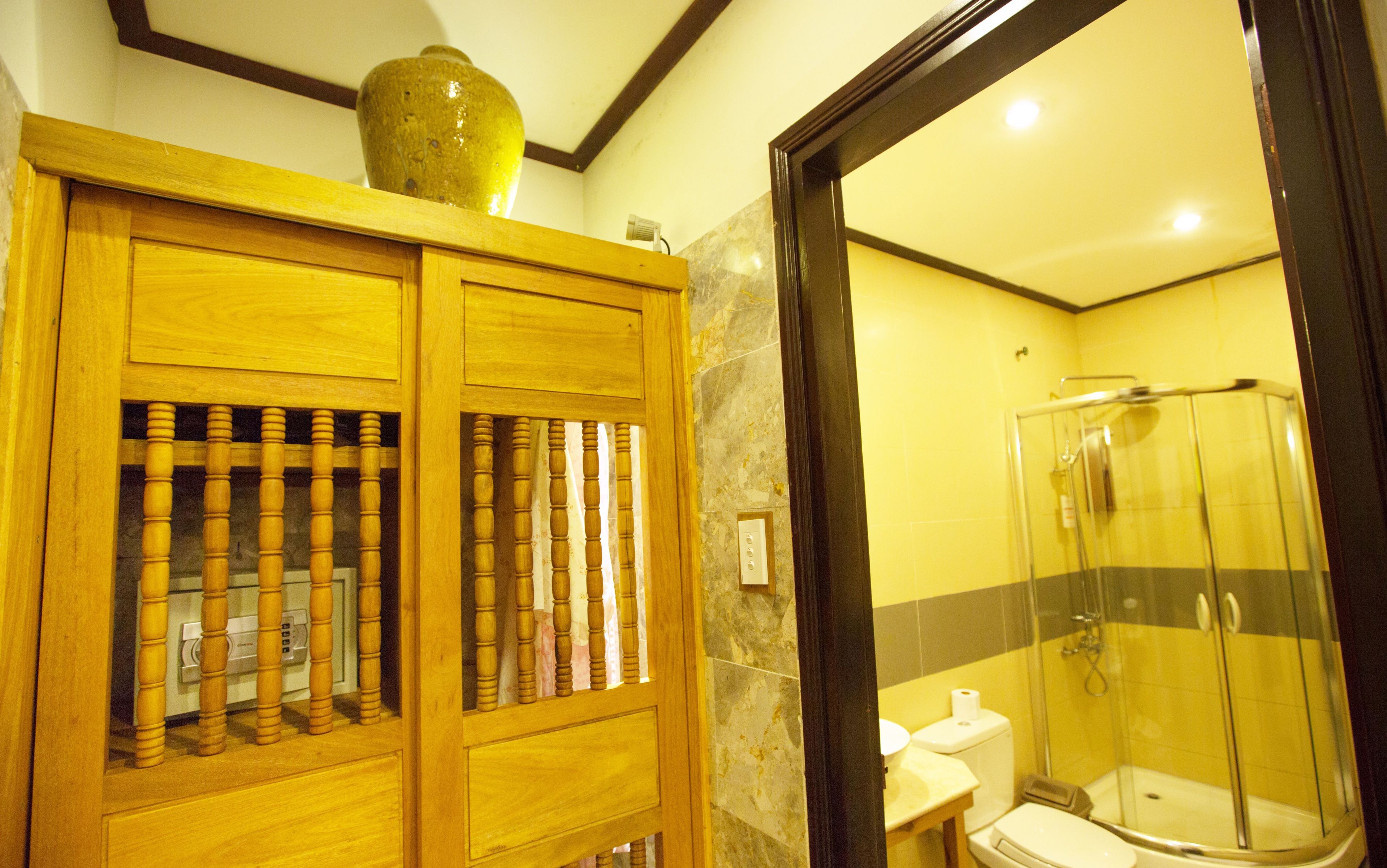 Une salle de bain avec un meuble en bois, des toilettes et une douche fermée par une paroi de verre.