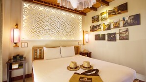 A hotel room with a large bed, decorative wall panels, and framed pictures on the wall. - Hoi An Pho Library Hotel (Da Nang)