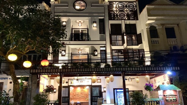 A multi-story building with a restaurant at the ground level, featuring outdoor seating and a signboard. - Hoi An Pho Library Hotel (Da Nang)