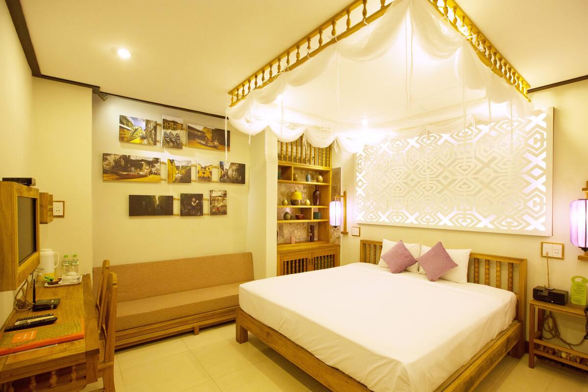 A bedroom with a bed, bedside table, lamp, and wall decor.