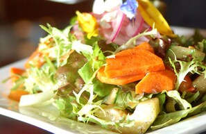 Une vue rapprochée d’une salade composée de différents légumes et de différentes feuilles vertes.