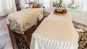 A room with two beds, a ceiling fan, a window with curtains, and a patterned rug.