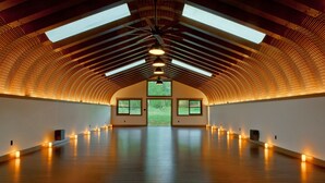 A spacious room with a high ceiling, skylights, and a large window at the far end.