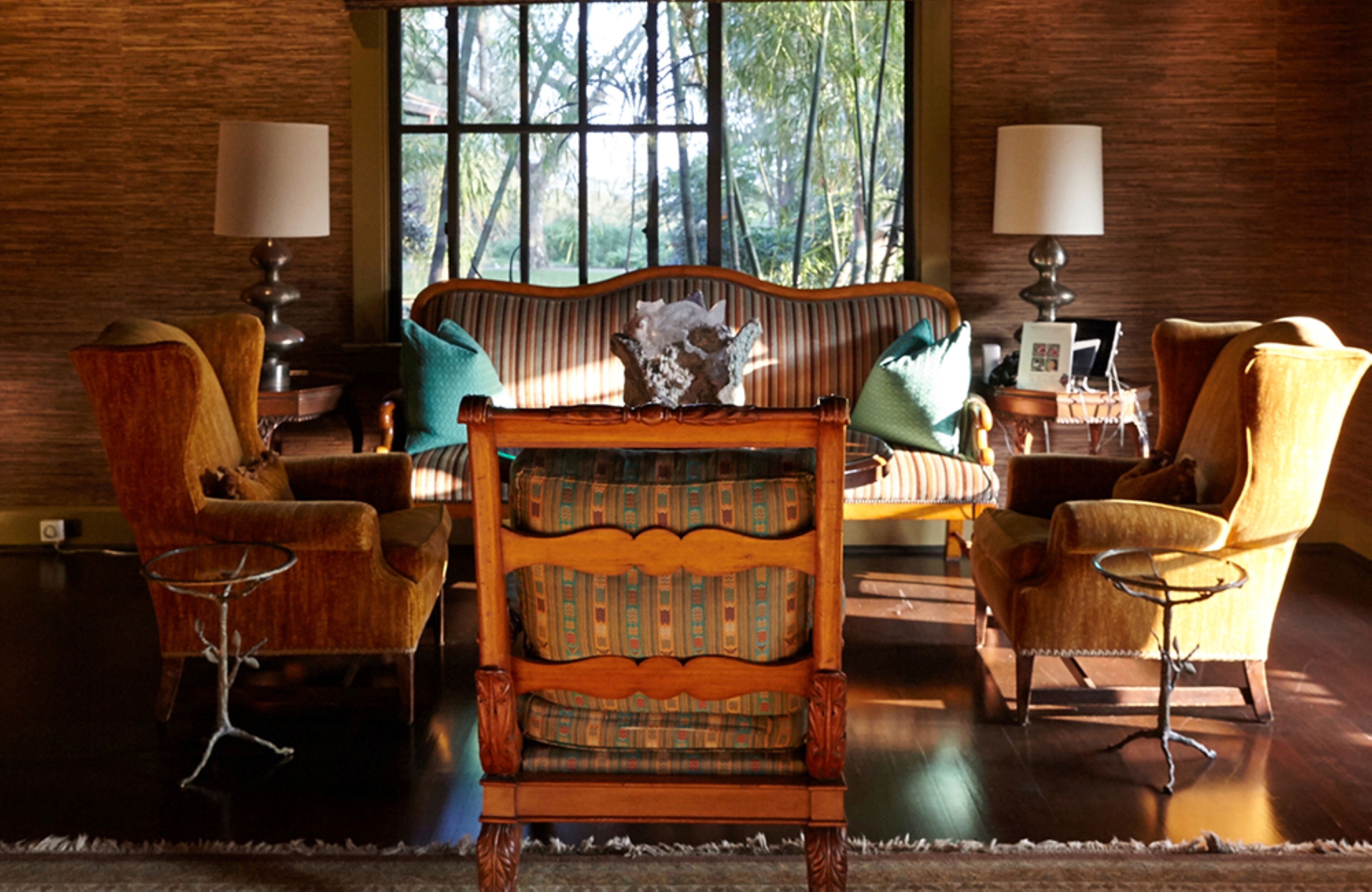 A living room with a wooden sofa, two armchairs, and a coffee table.