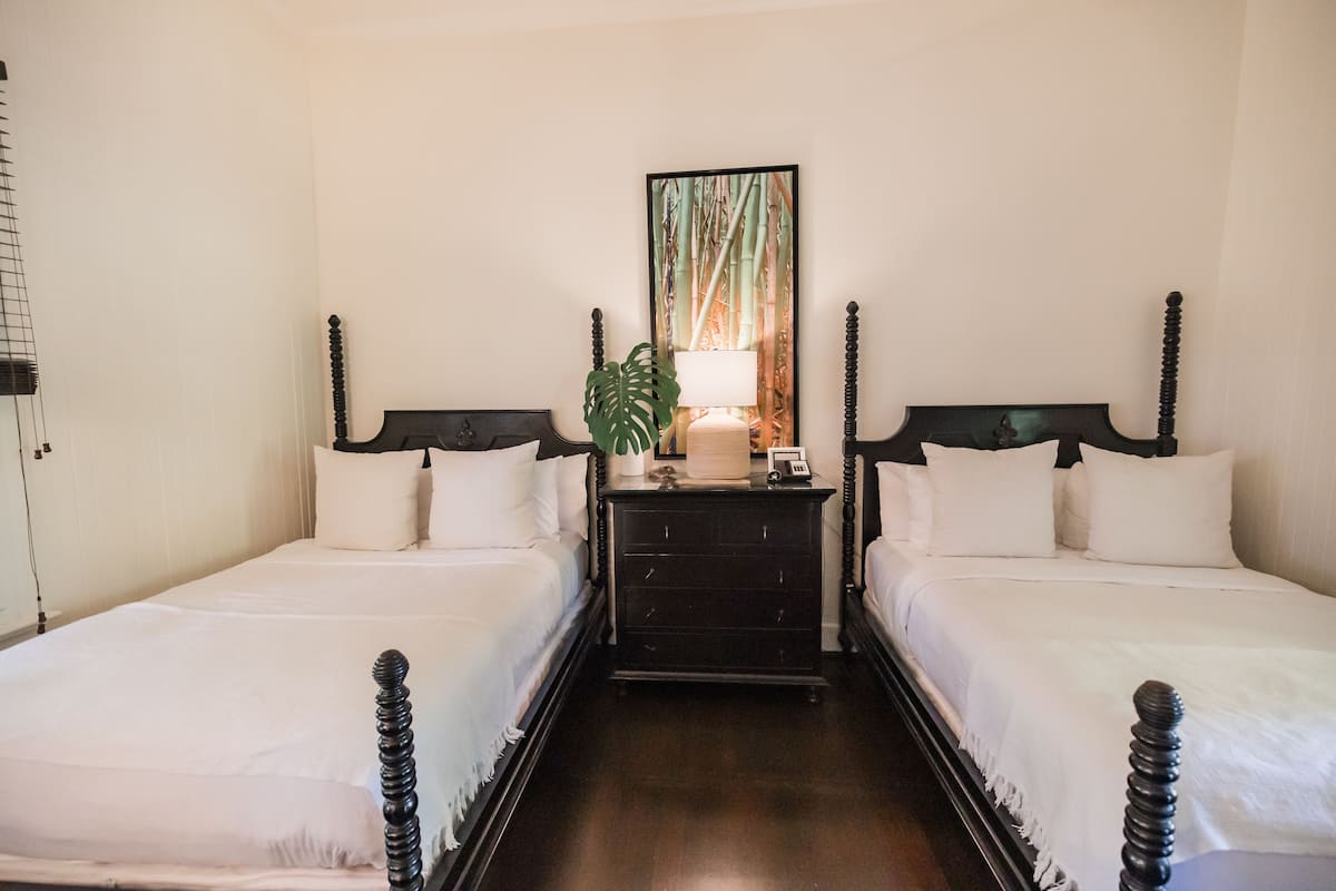 A double bed with a wooden headboard, a bedside table with a lamp, and a framed picture on the wall.