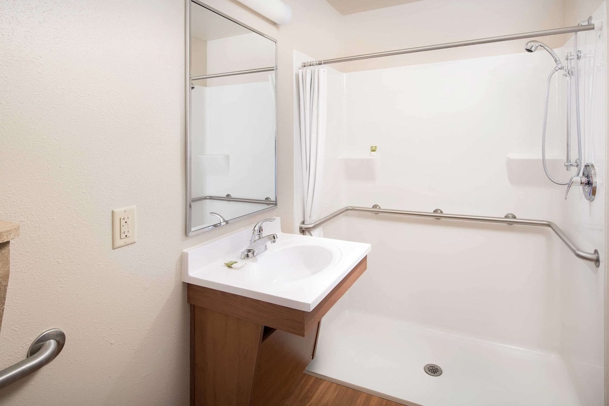 A bathroom with a white sink, mirror, and shower.