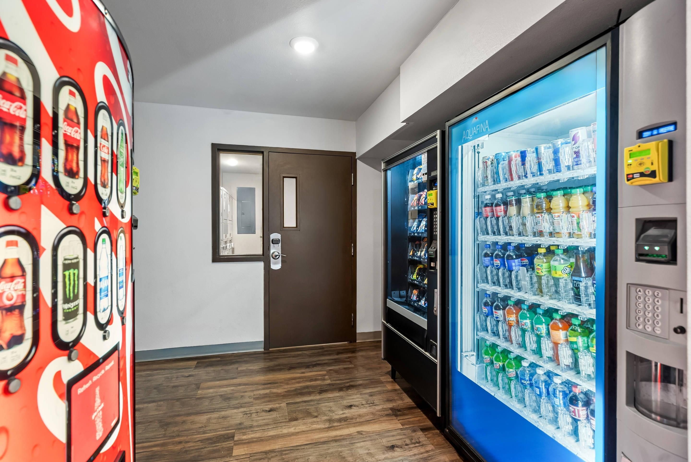 A hallway with a vending machine on the right and a Coca-Cola themed wall on the left.