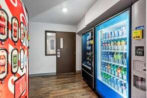 A hallway with a vending machine on the right and a Coca-Cola themed wall on the left. - WoodSpring Suites Richmond West I-64 (Richmond)