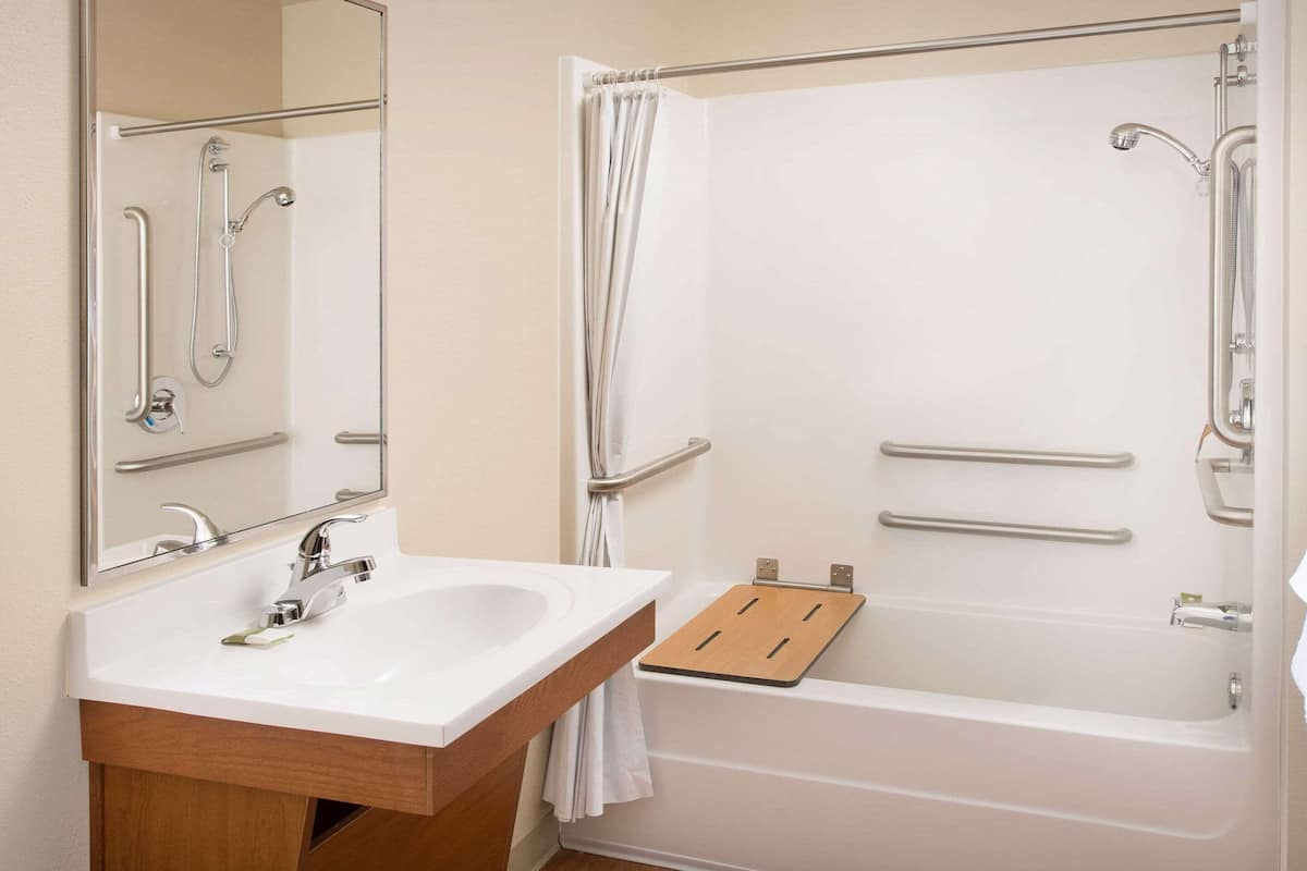A bathroom with a white sink, mirror, and bathtub.