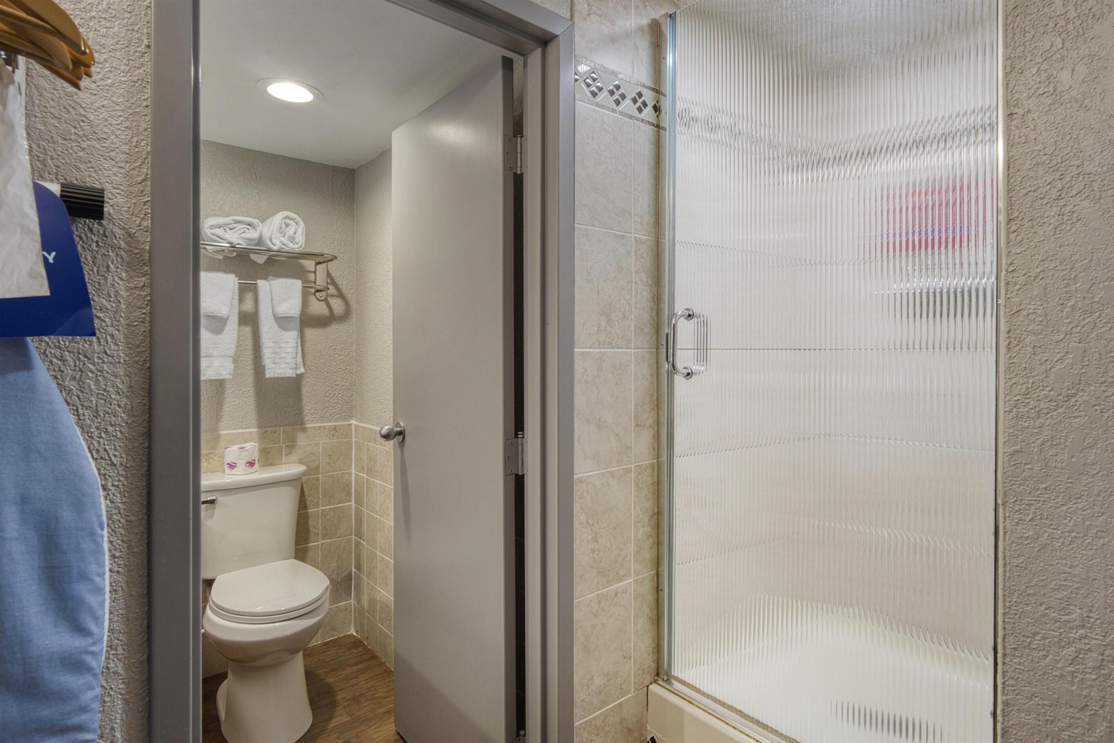 Un baño con inodoro, cabina de ducha de vidrio y barra para toallas.