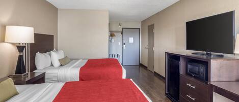 Habitación de hotel con dos camas, televisor, escritorio y microondas.