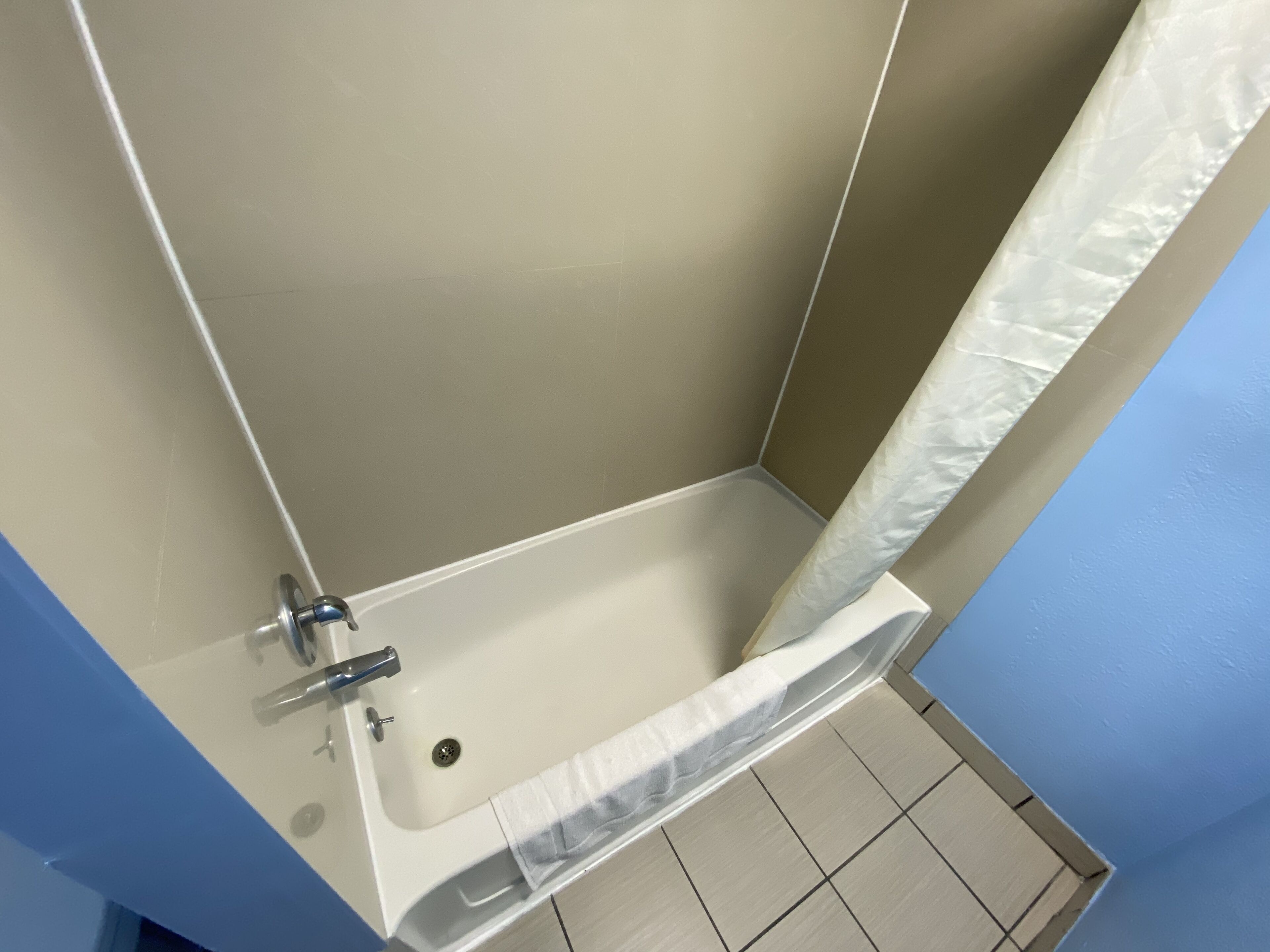 A bathroom with a bathtub, a shower curtain, and a tiled floor.