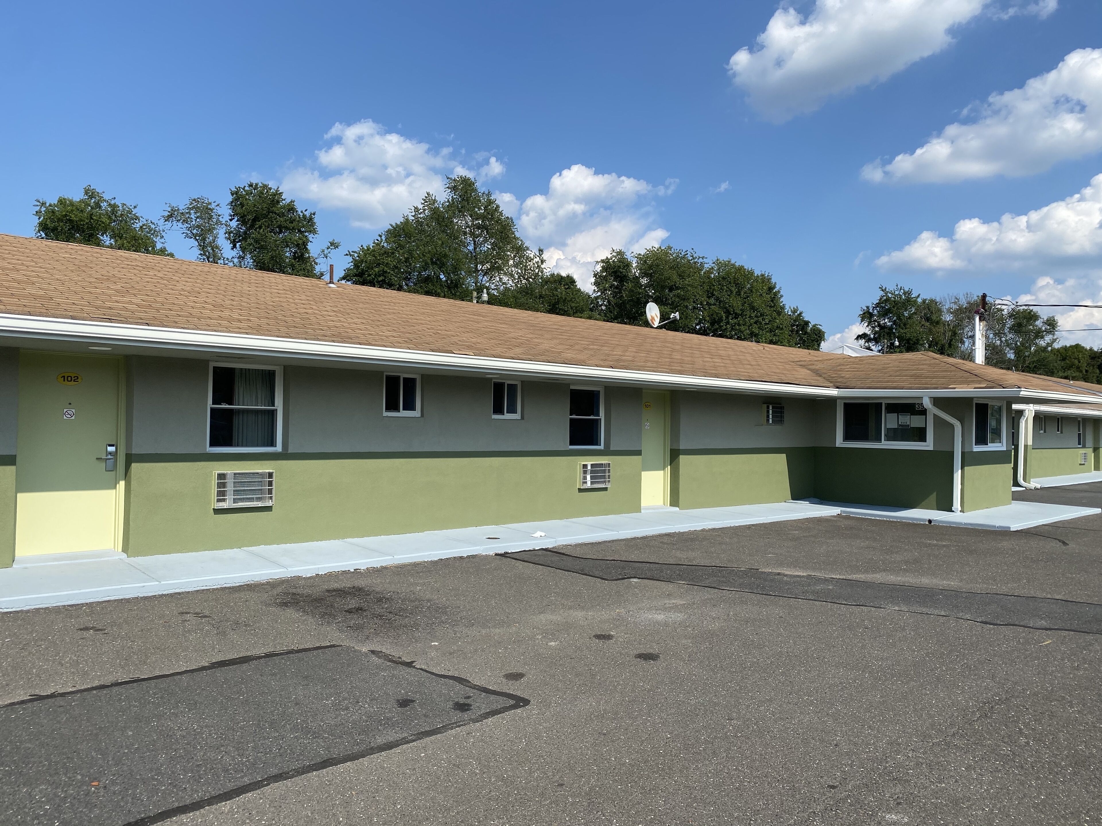 A motel with a row of rooms, each with a window and a door.