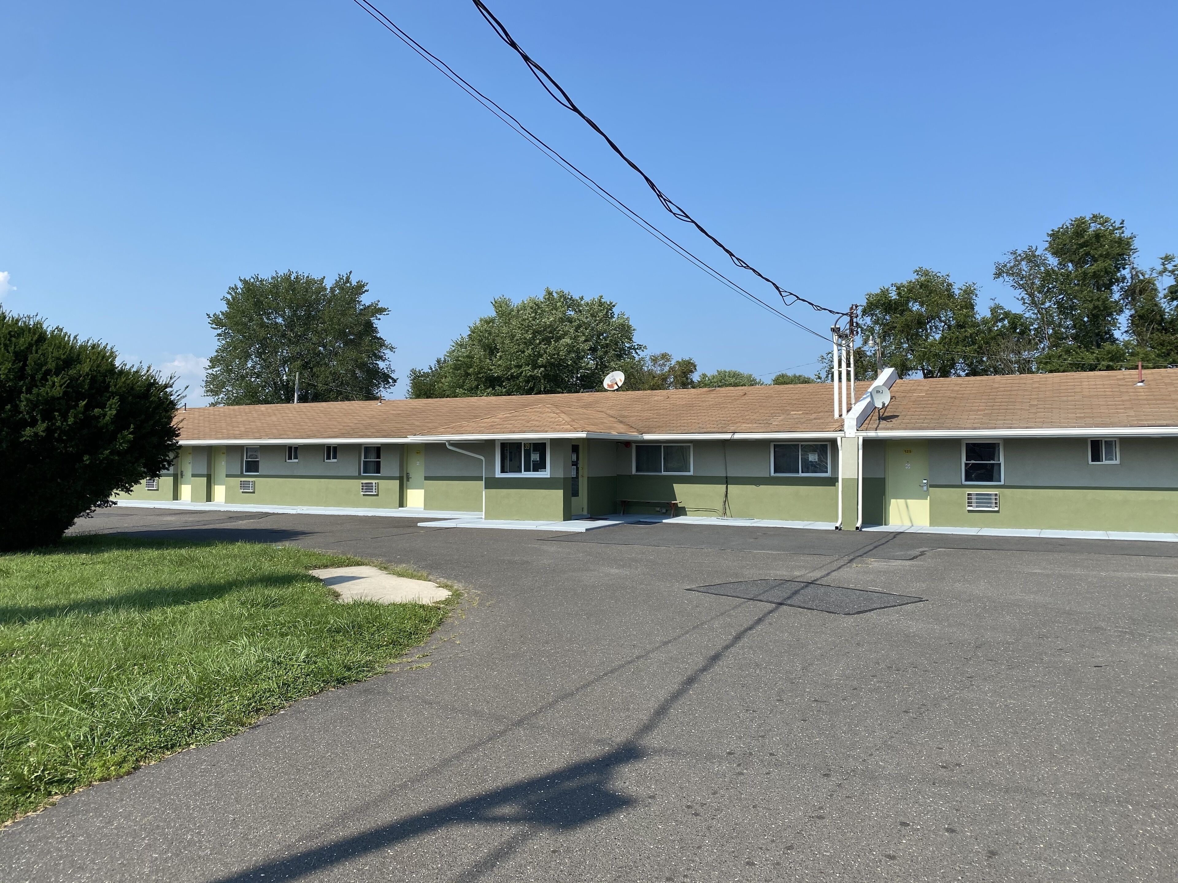 Un motel à l’extérieur vert, doté de nombreuses fenêtres et d’un parking.