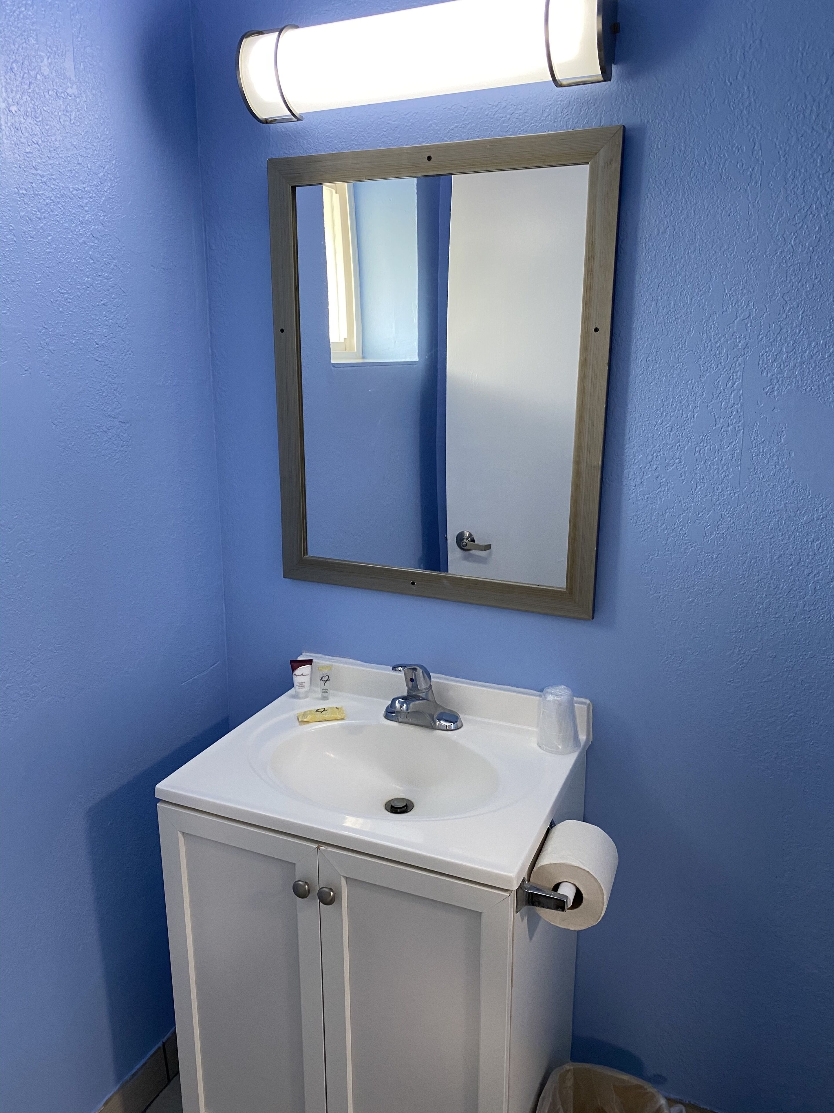 A bathroom with a white sink, a mirror, and a blue wall.