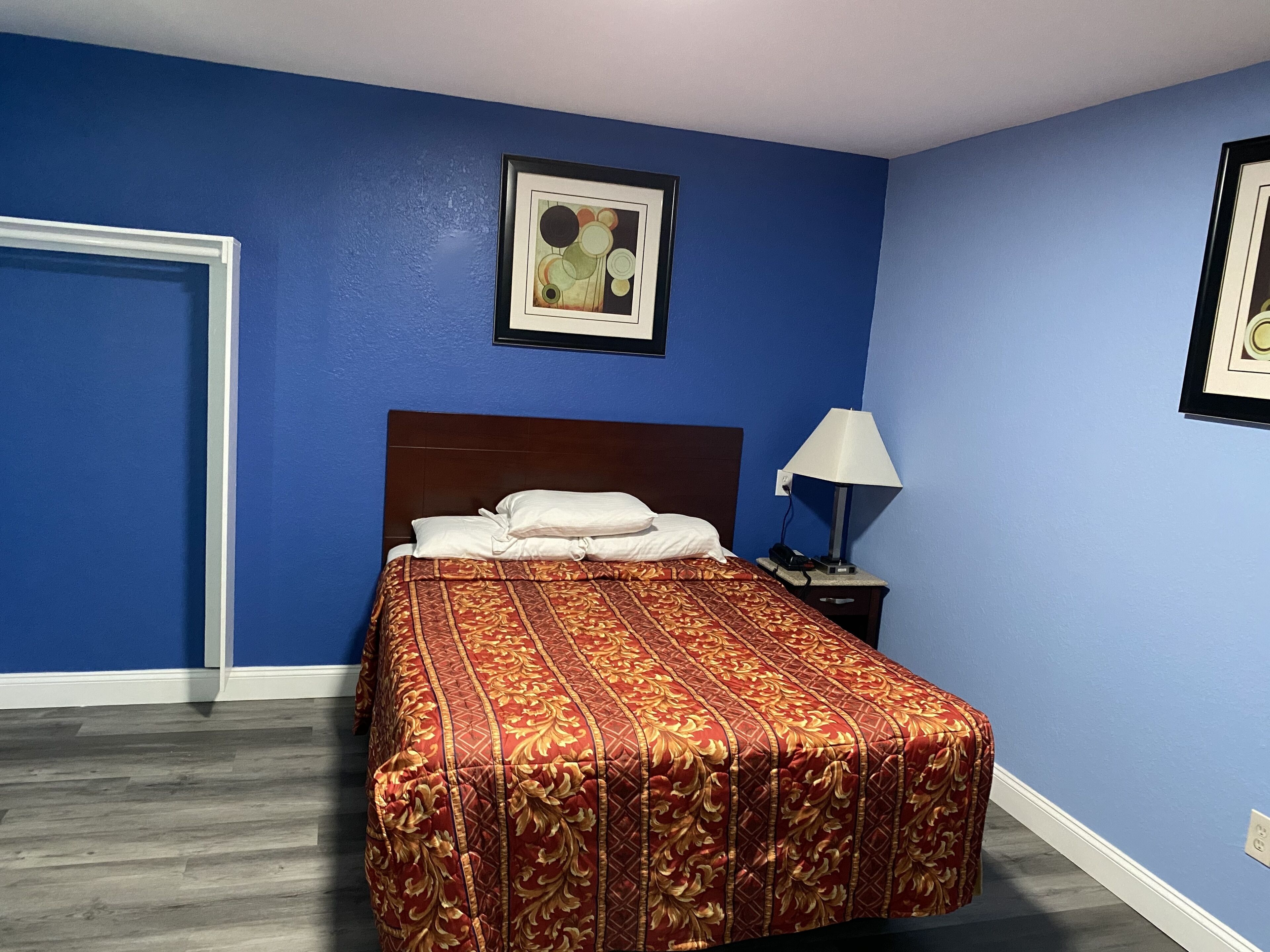 Une chambre d’hôtel avec un lit, une table de chevet, une lampe et un tableau encadré au mur.