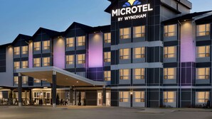 Un hotel Microtel by Wyndham con un diseño moderno, que cuenta con varios pisos y un área de entrada techada.