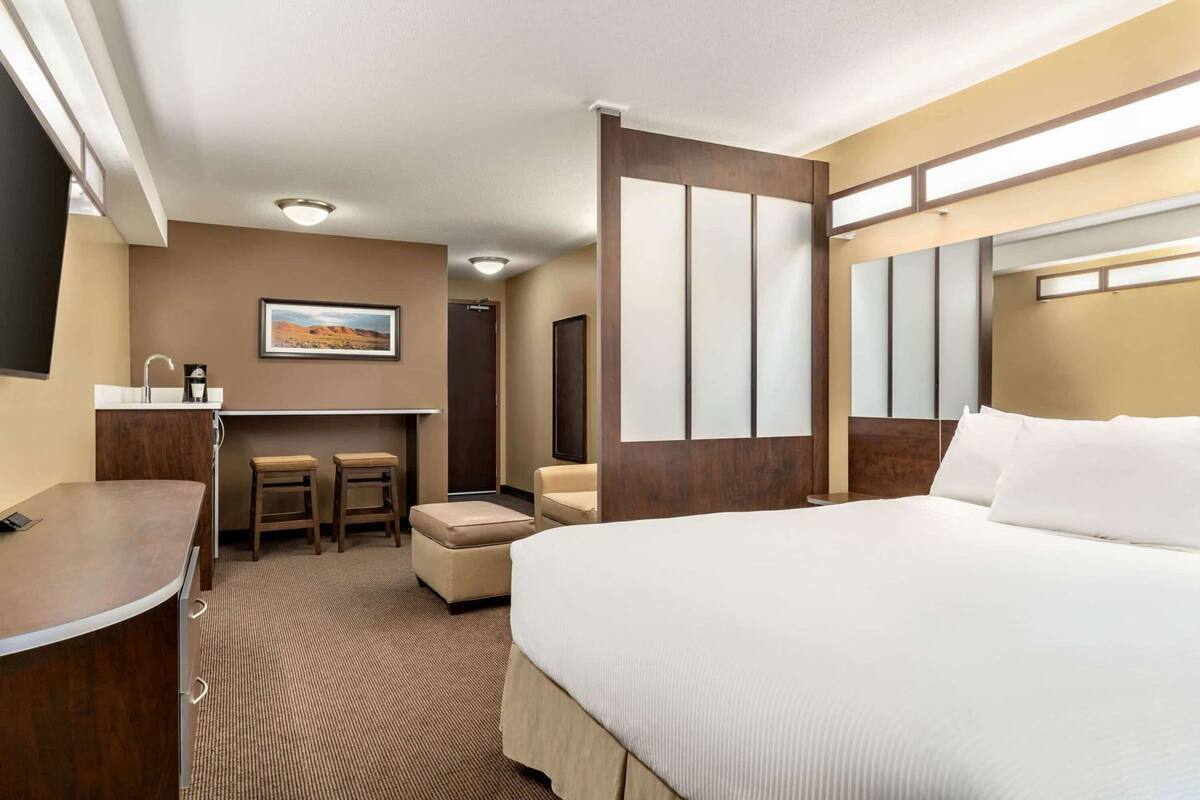 Ein Hotelzimmer mit Bett, Schreibtisch mit Stuhl, einem kleinen Tisch und einer Couch.