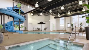 Una piscina interior con un tobogán azul, sillas de descanso y plantas en macetas.