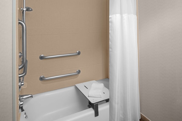 Une salle de bain équipée d’une baignoire, de barres d’appui et d’un porte-serviettes.