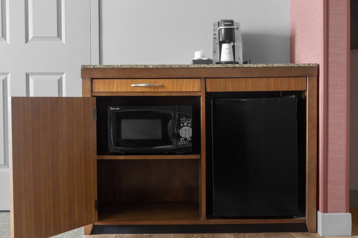 Eine kleine Küche mit einer Mikrowelle, einer Kaffeemaschine und einem Kühlschrank.