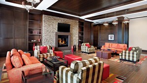 Una sala moderna con chimenea de piedra, sofás a rayas y un sofá rojo de acento.