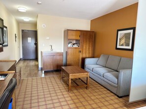A compact living area with a kitchenette, a sofa, a coffee table, and a patterned rug. - Four Points By Sheraton Edmonton Gateway (Edmonton)