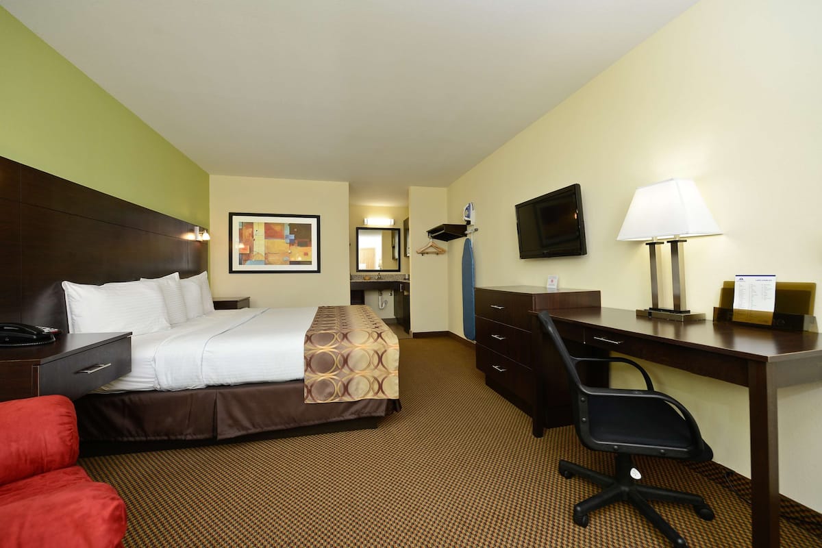 A hotel room with a bed, desk, chair, and a television on the wall.