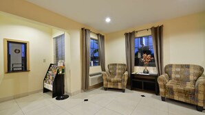 A living room with two armchairs, a small table, a standing lamp, and a door with a window.