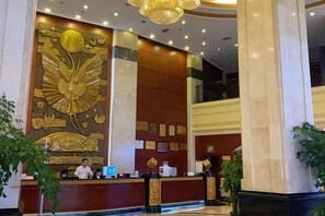 A hotel lobby with a large golden mural, a reception desk, and a staircase. - Fuling Hotel (Chongqing)