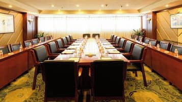 A conference room with a long table, multiple chairs, and a carpeted floor.