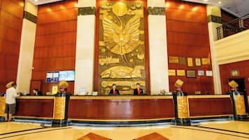 A hotel reception area with a large decorative wall, reception desk, and a polished floor.
