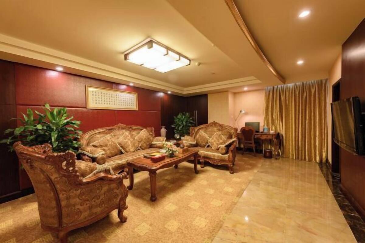 A room with a sofa set, a coffee table, a television, and a curtain.