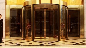 Une porte tournante dotée de panneaux de verre et d’un cadre métallique, qui donne accès à l’entrée d’un bâtiment.