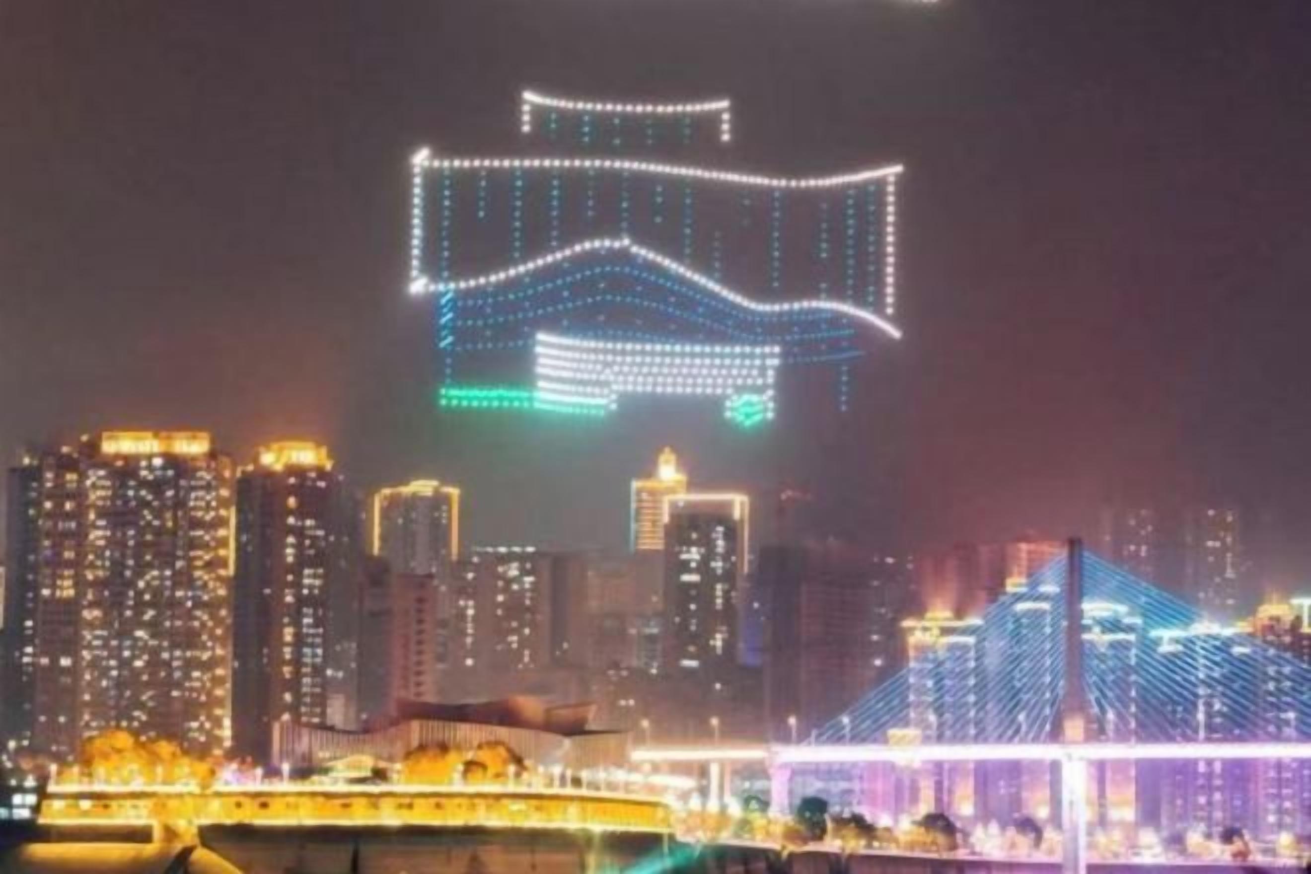 A cityscape at night with illuminated buildings and a bridge.