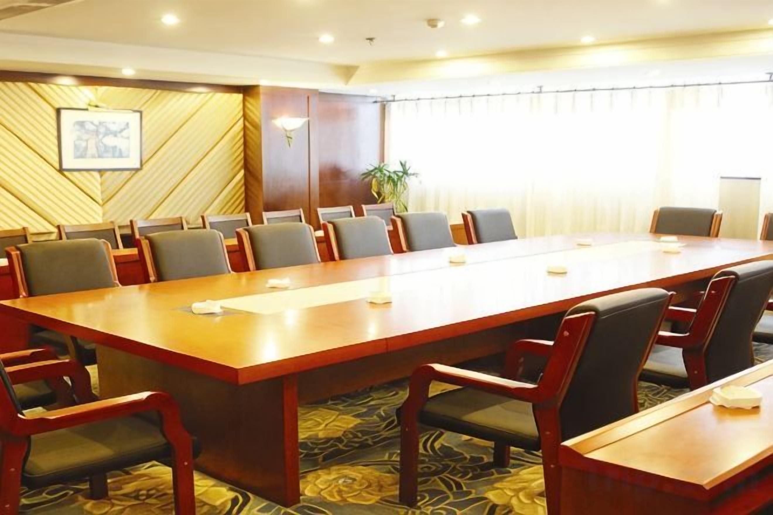 A conference room with a long table, multiple chairs, and a patterned carpet.