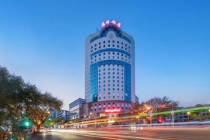 A tall hotel with a blue and white facade, multiple floors, and a prominent sign at the top.