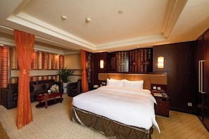 A hotel room with a large bed, a sofa, a coffee table, and a desk. - Fuling Hotel (Chongqing)