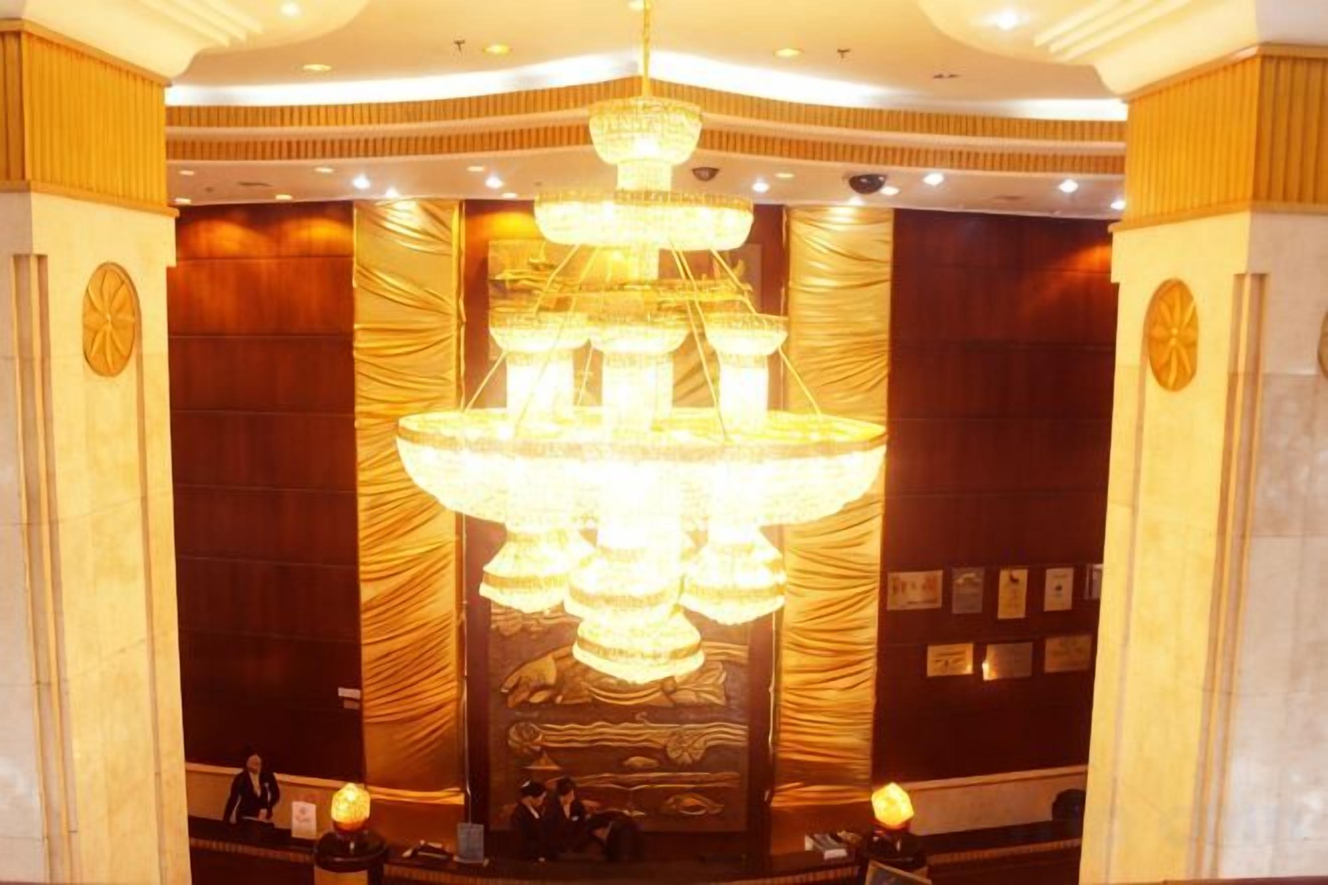 A lobby with a large chandelier, wooden paneling, and a reception desk.