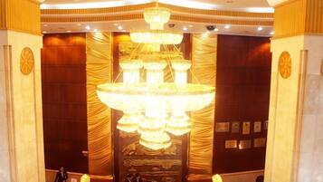 A lobby with a large chandelier, wooden paneling, and a reception desk.