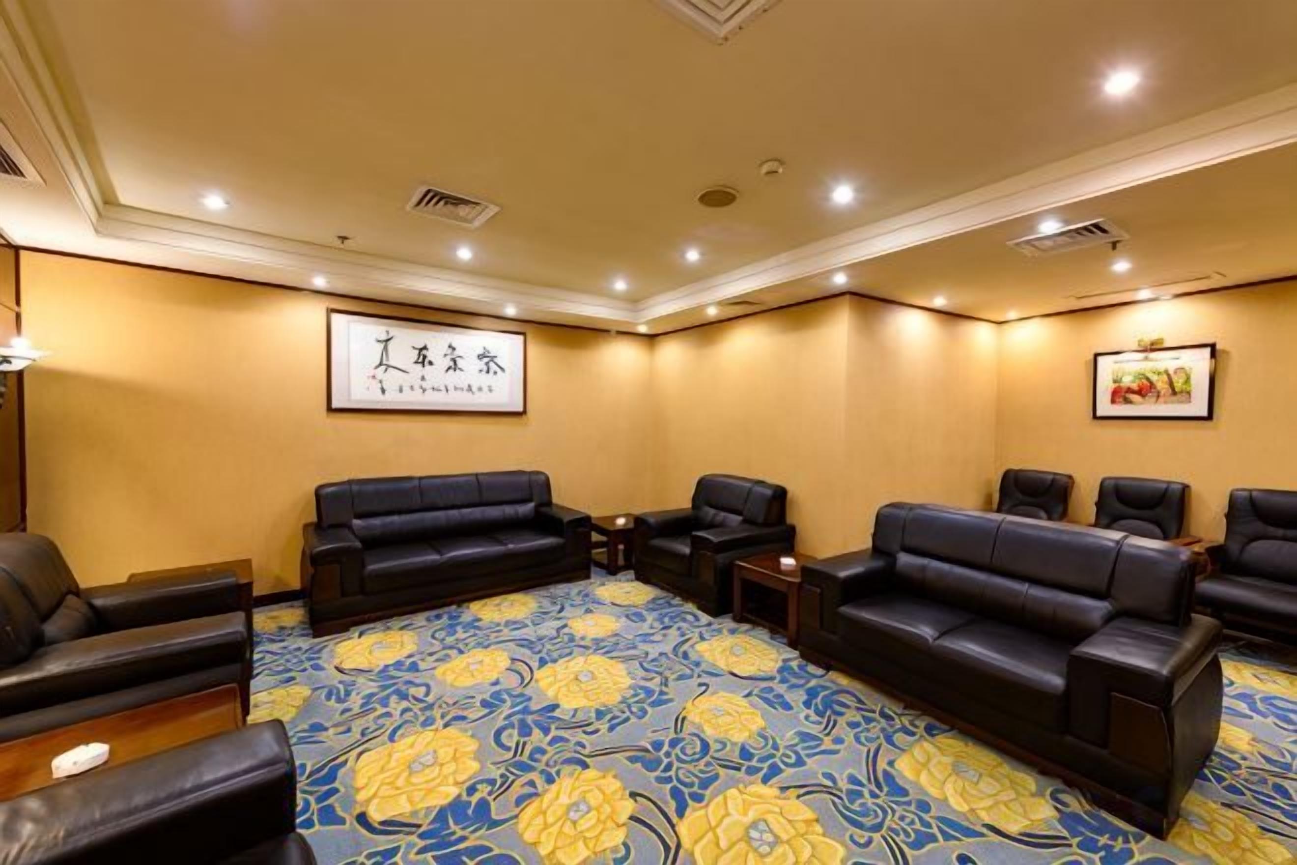 A conference room with a large carpet, multiple sofas, and chairs arranged for meetings.