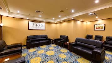 A conference room with a large carpet, multiple sofas, and chairs arranged for meetings.