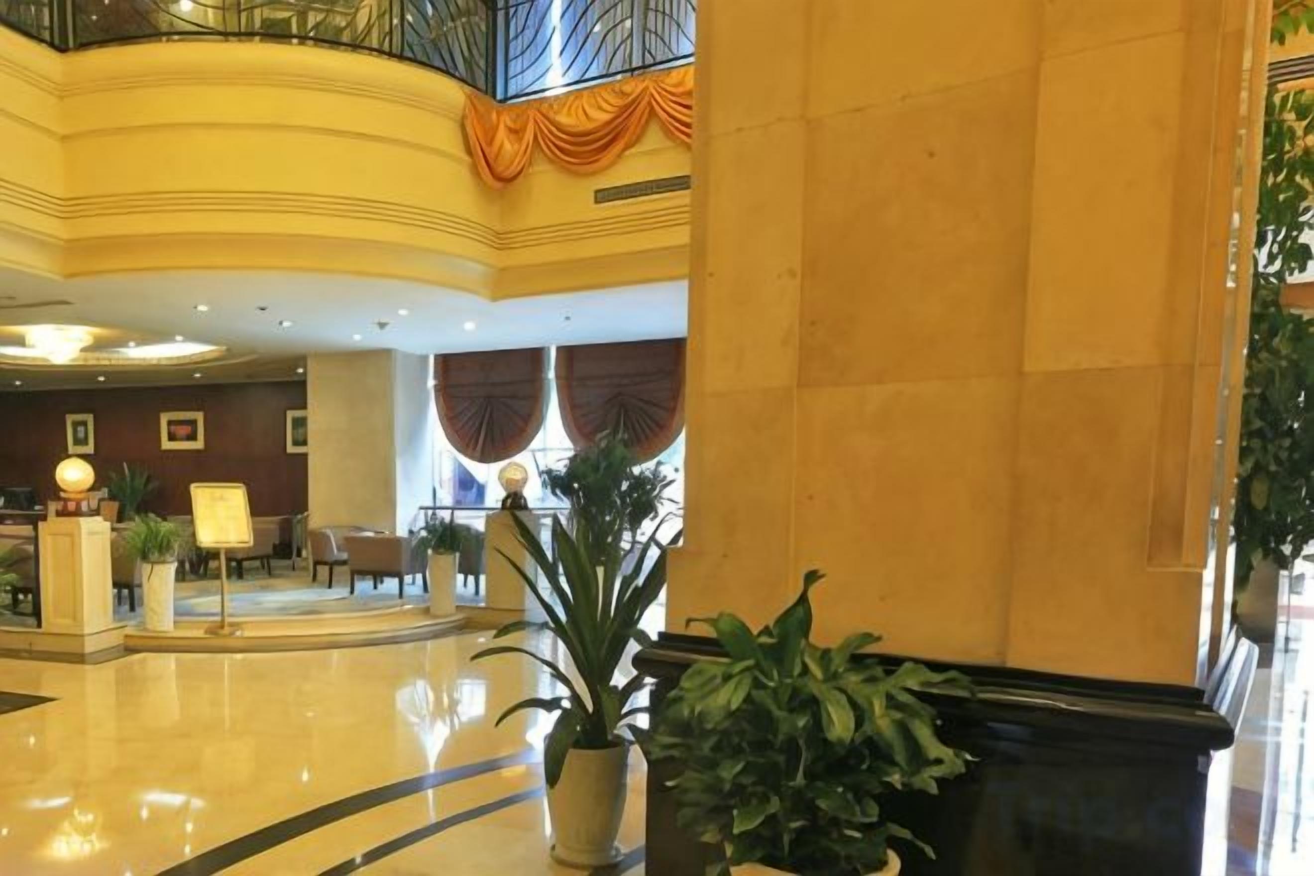 A hotel lobby with a reception desk, seating area, and a staircase.