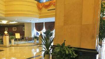 A hotel lobby with a reception desk, seating area, and a staircase.