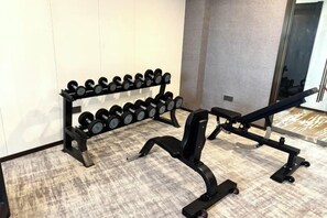 A gym with a bench press and a dumbbell rack. - Fuling Hotel (Chongqing)