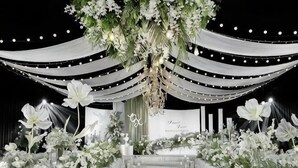 Une scène agrémentée d’une composition florale, de draperies et d’une enseigne.