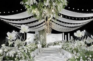 Un escenario con una decoración floral, tela drapeada y un cartel.