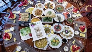 Une table de salle à manger ronde, sur laquelle on trouve différents plats et ustensiles.