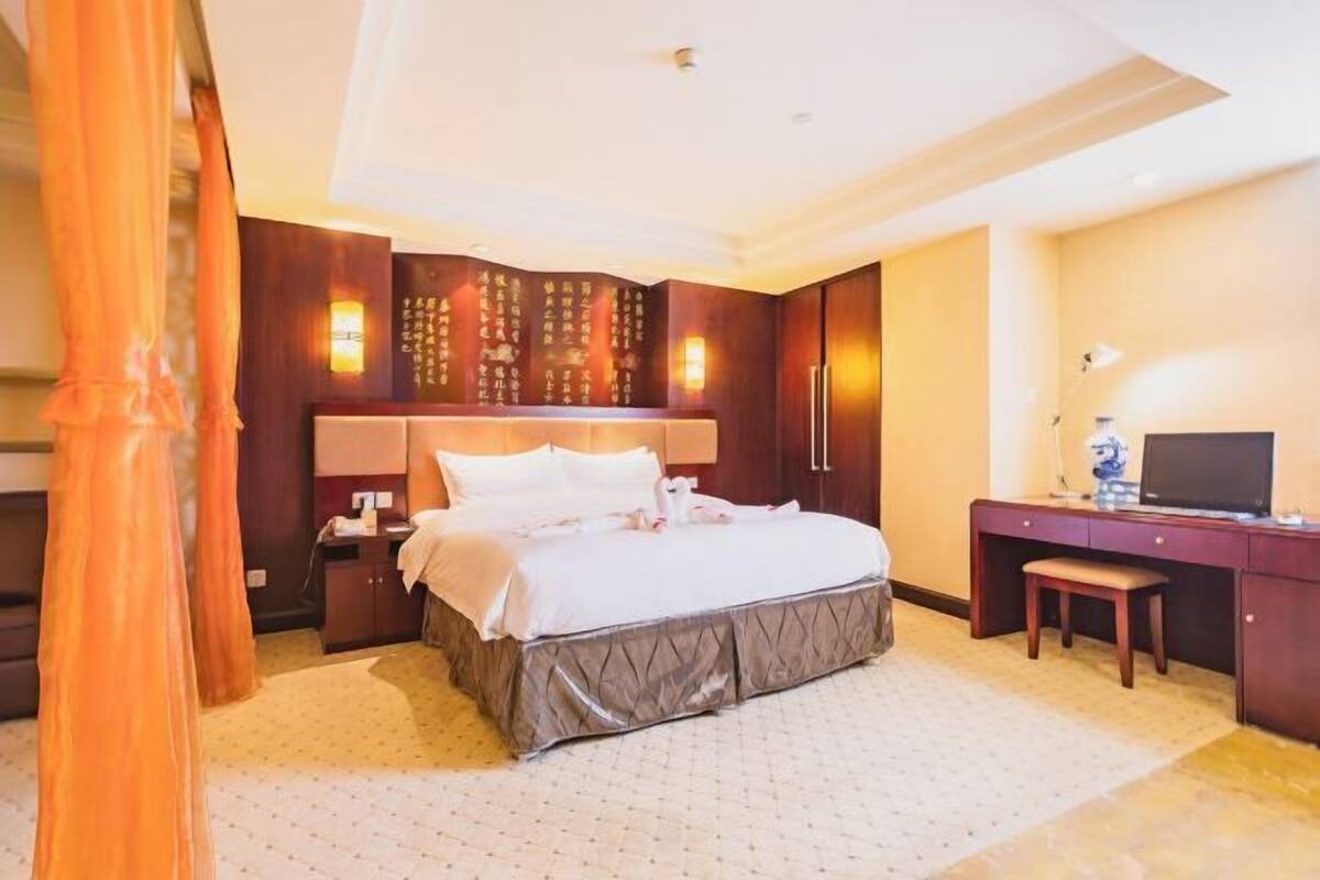 A hotel room with a bed, desk, chair, and a television.